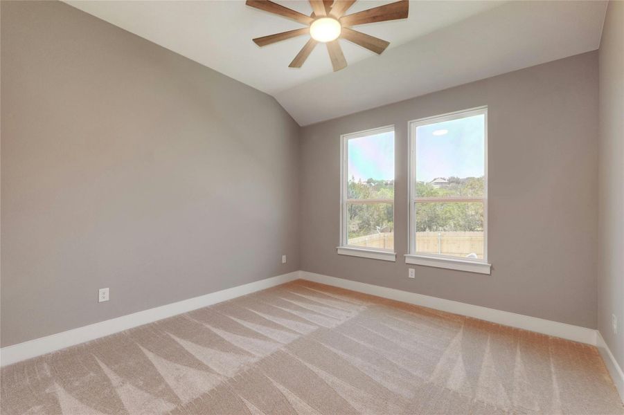 Room featuring two large windows with white trim, a vaulted ceiling, and a ceiling fan with wood-finish blades