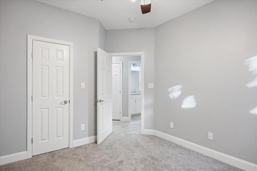 Secondary bedroom with ceiling fan and light carpet