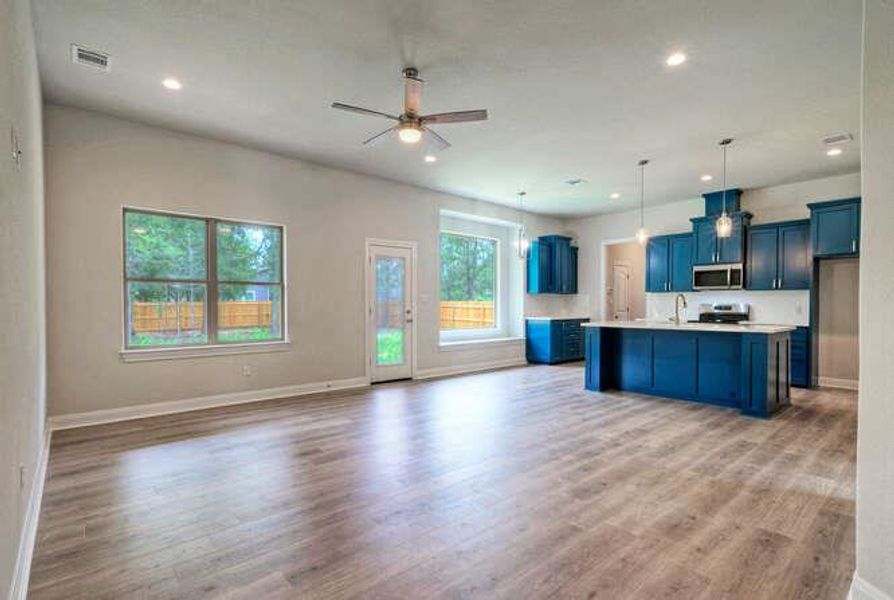 Kitchen featuring open floor plan, a ceiling fan, light countertops, light wood finished floors, and recessed lighting