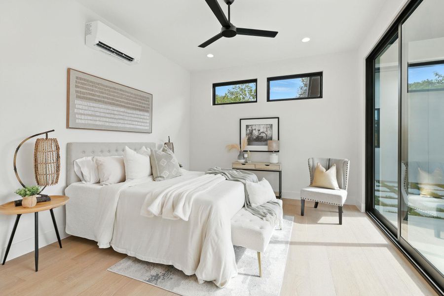 Bedroom featuring access to exterior, multiple windows, light wood-type flooring, recessed lighting, and an AC wall unit Bedroom featuring access to exterior, multiple windows, light wood-type flooring, recessed lighting, and an AC wall unit