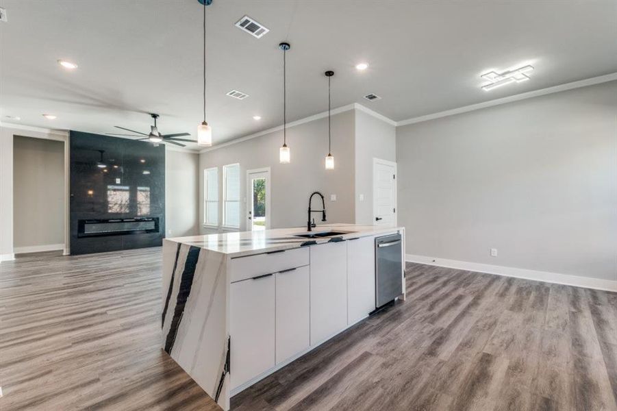 Kitchen featuring white cabinets, open floor plan, ceiling fan, decorative light fixtures, and light wood-style floors
