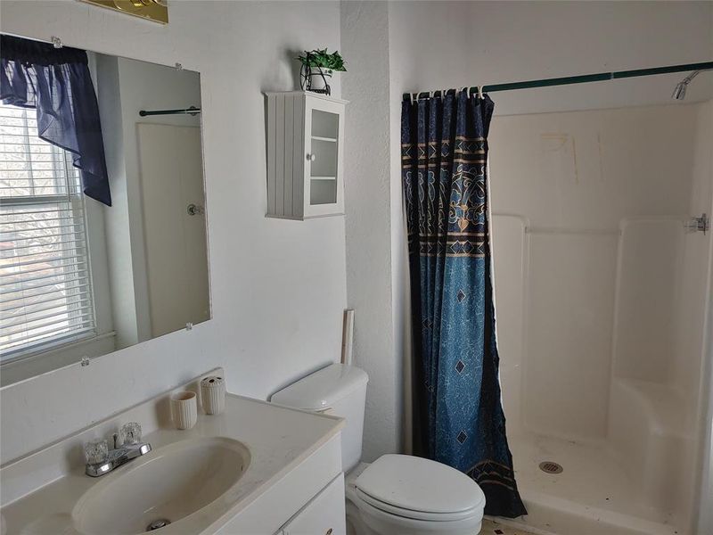 Bathroom featuring a single vanity, wall-mounted mirror, white wall cabinet, and a walk-in shower with an integrated bench seat Bathroom featuring a single vanity, wall-mounted mirror, white wall cabinet, and a walk-in shower with an integrated bench seat