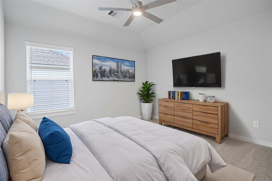 Secondary bedroom features plush carpet, custom paint, ceiling fan with lighting and a large window with privacy blinds.