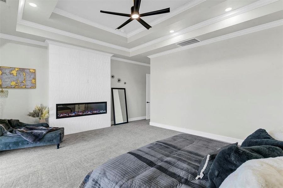 Living room featuring crown molding, a raised ceiling, carpet floors, and a fireplace