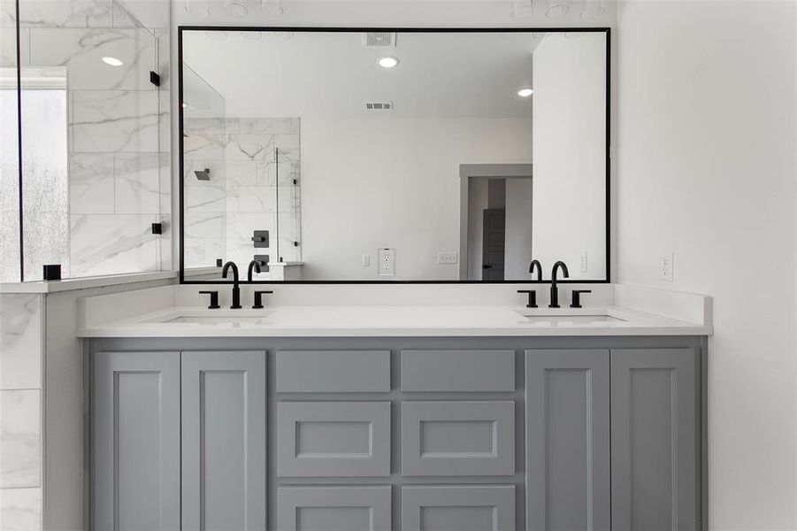 Bathroom featuring double vanity, a marble finish shower, and recessed lighting