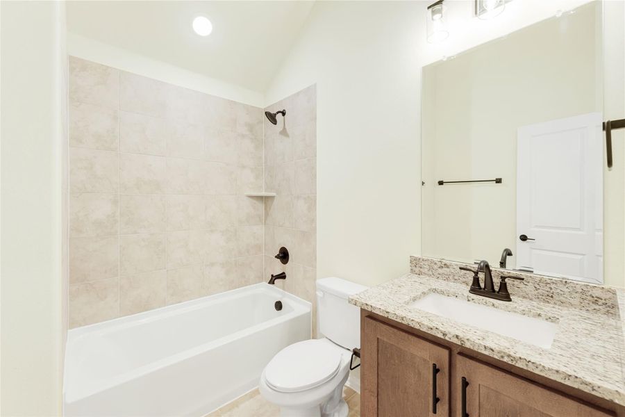 Bathroom with tiled tub-shower combo, granite vanity, and wood cabinets with dark hardware Bathroom with tiled tub-shower combo, granite vanity, and wood cabinets with dark hardware