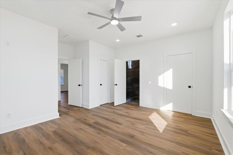 The primary suite offers not one but two walk-in closets, eliminating any shortage of storage. Modern ceiling fans, recessed lighting, and sleek black hardware complete the space. The primary suite offers not one but two walk-in closets, eliminating any shortage of storage. Modern ceiling fans, recessed lighting, and sleek black hardware complete the space.