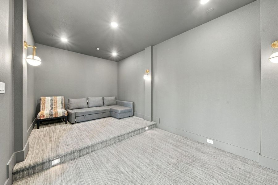 Movie nights just got an upgrade in this spacious media room, complete with a raised seating platform and soft sconce lighting for the perfect ambiance. Wall-to-wall carpet keeps the space comfortable and quiet.