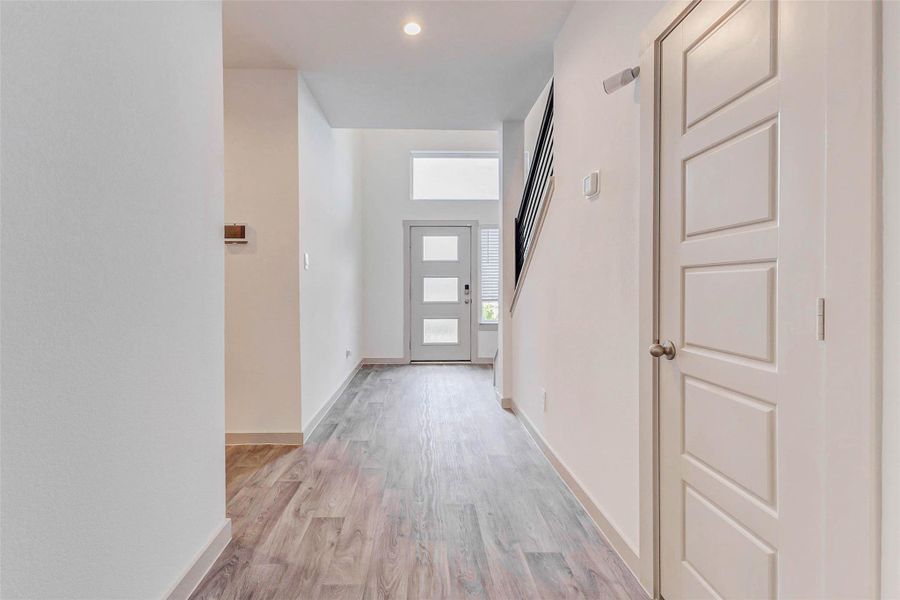 Natural light pours into the foyer through modern glass door panels and transom window above, highlighting the home’s high ceilings and spacious entry. Durable, beautiful low-maintenance flooring continues throughout the main level, creating a seamless flow between rooms and adding warmth to the minimalist design. Natural light pours into the foyer through modern glass door panels and transom window above, highlighting the home’s high ceilings and spacious entry. Durable, beautiful low-maintenance flooring continues throughout the main level, creating a seamless flow between rooms and adding warmth to the minimalist design.