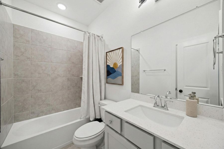 THIS BATHROOM FEATURES A TUB/SHOWER COMBO WITH TILE WALLS AND A VANITY WITH A WHITE COUNTERTOP.
