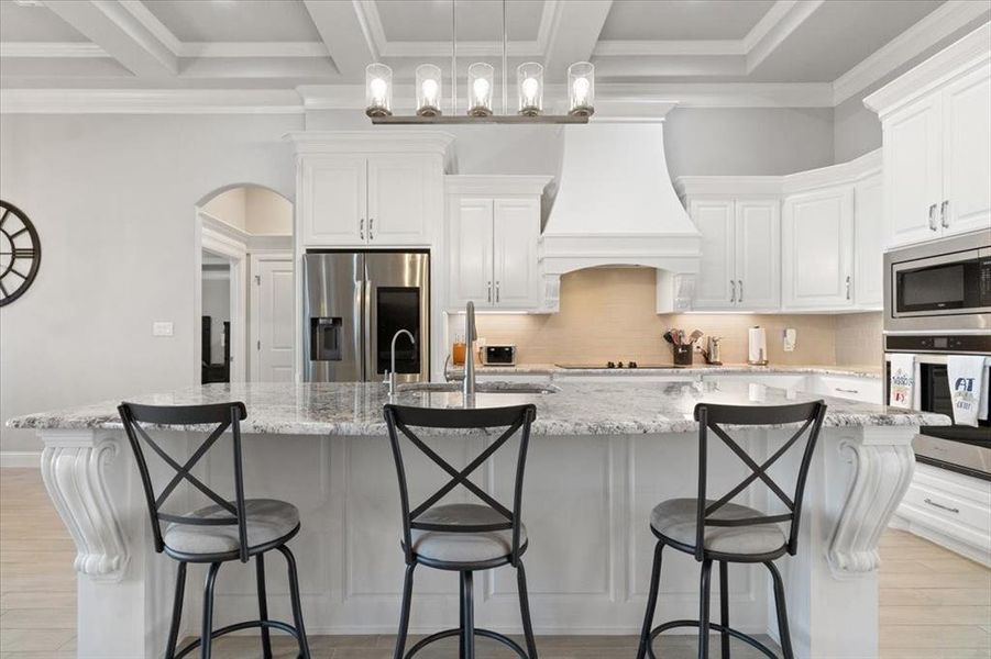 Kitchen featuring a breakfast bar, a spacious island, custom exhaust hood, and stainless steel appliances