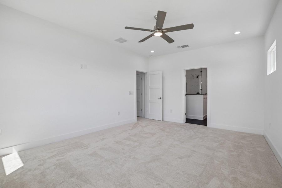 Soft carpeting underfoot defines this inviting bedroom featuring clean lines and recessed lighting.