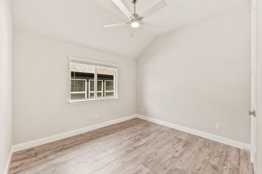 Empty bedroom with vaulted ceiling, ceiling fan, hardwood floors, and single window Empty bedroom with vaulted ceiling, ceiling fan, hardwood floors, and single window