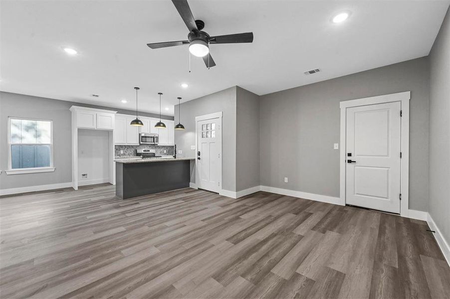 Unfurnished living room featuring ceiling fan and hardwood / wood-style flooring