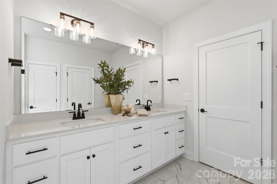 Spa-like ensuite with dual vanities, generous storage, and a crisp, modern finish.