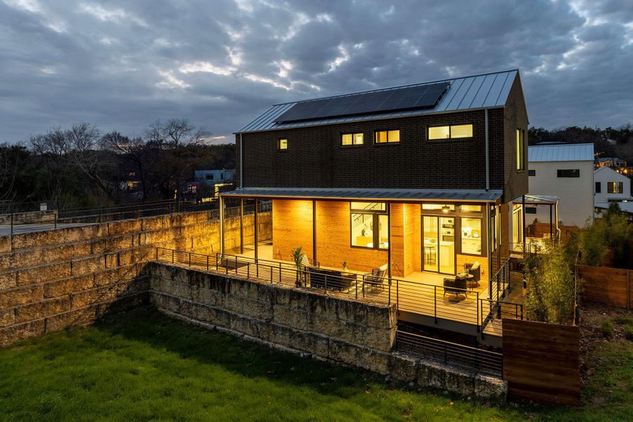 Back of house featuring metal roof, fence private yard, solar panels, brick siding, and a standing seam roof