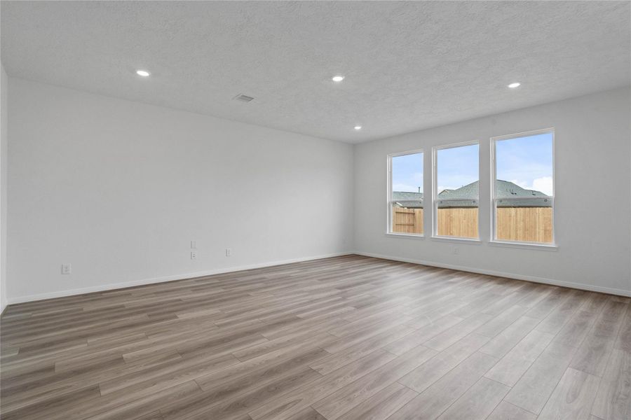 Gather the family and guests together in your lovely family room! Featuring high ceilings, recessed lighting, custom paint, gorgeous vinyl plank floors, and large windows showcasing views of the backyard space. Gather the family and guests together in your lovely family room! Featuring high ceilings, recessed lighting, custom paint, gorgeous vinyl plank floors, and large windows showcasing views of the backyard space.