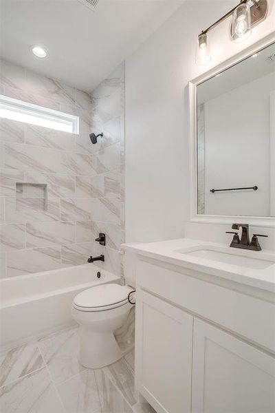 Full bathroom with tiled shower / bath combo, vanity, and toilet