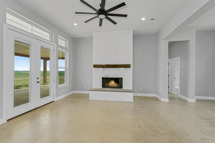 Unfurnished living room with french doors, concrete flooring, baseboards, a ceiling fan, and recessed lighting