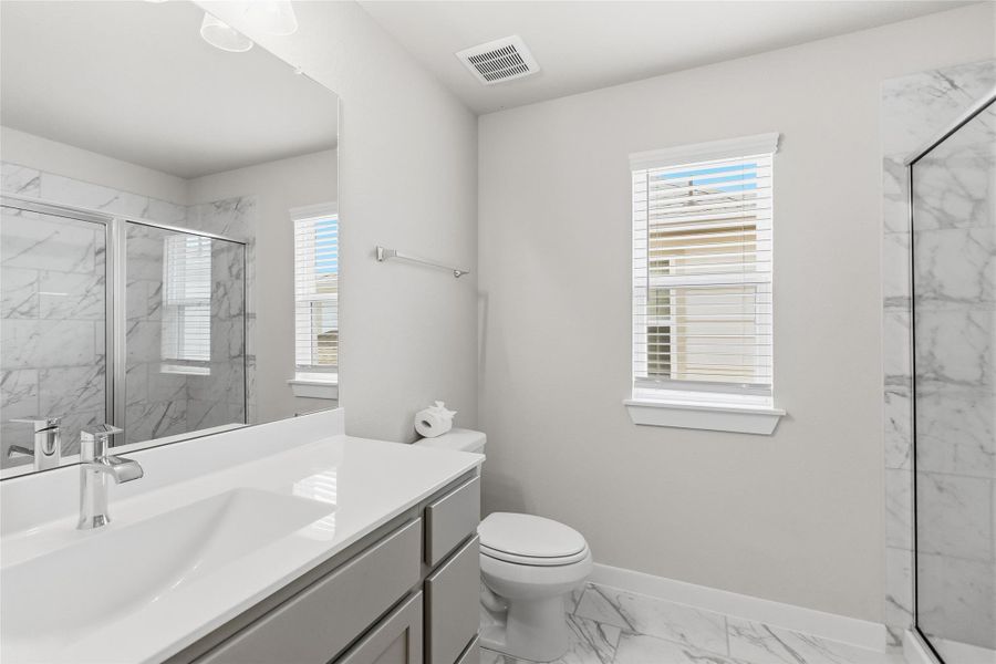 Your well-appointed full bathroom features a sleek vanity, quartz countertops, and a beautifully tiled walk-in shower with contemporary finishes.