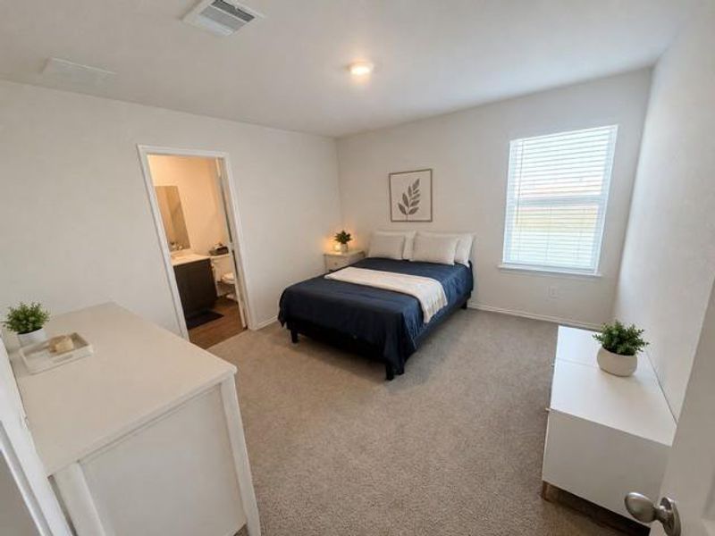 Carpeted bedroom featuring a single window with blinds and an attached bathroom Carpeted bedroom featuring a single window with blinds and an attached bathroom