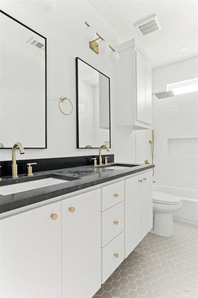 Full bathroom with tile floors, washtub / shower combination, toilet, and double sink vanity