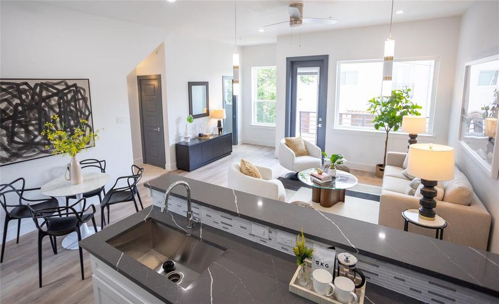 Kitchen featuring decorative light fixtures, ceiling fan, light wood-type flooring, and sink