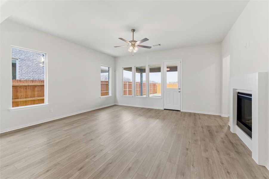 Unfurnished living room with a glass covered fireplace, light wood-style floors, and a ceiling fan Unfurnished living room with a glass covered fireplace, light wood-style floors, and a ceiling fan