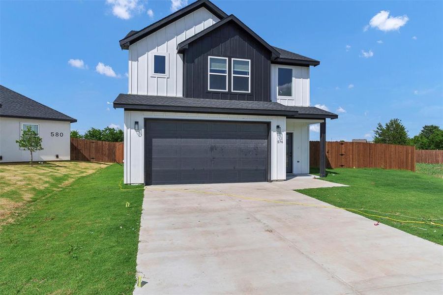 View of front of property featuring driveway, an attached garage, and board and batten siding