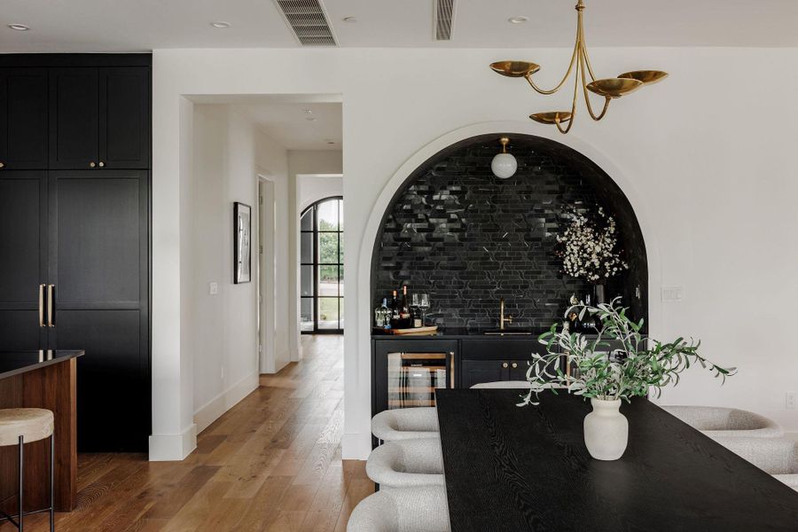 A sophisticated built-in bar connects seamlessly to the living room, offering stylish counters and tile, custom cabinetry, and the perfect atmosphere for entertaining. A sophisticated built-in bar connects seamlessly to the living room, offering stylish counters and tile, custom cabinetry, and the perfect atmosphere for entertaining.