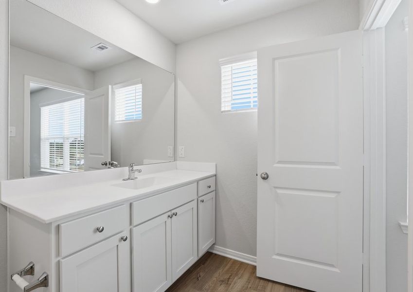 Primary bathroom vanity featuring a cultured marble countertop, large mirror, and a window with natural light.