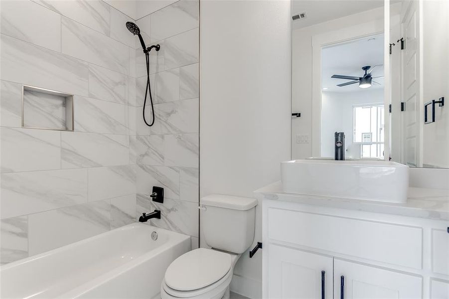 Full bathroom featuring tiled shower / bath, vanity, toilet, and ceiling fan