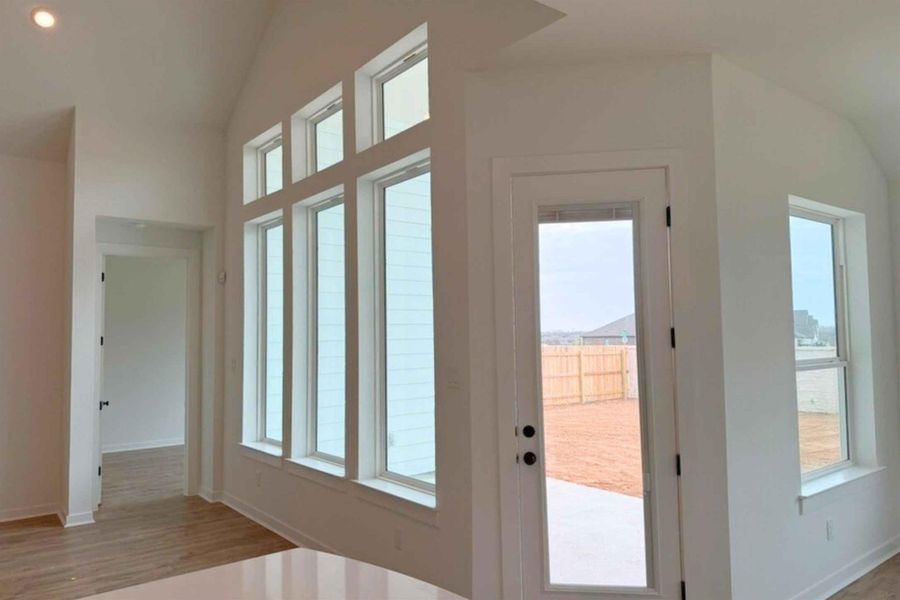 Doorway with vaulted ceiling, plenty of natural light, wood finished floors, and recessed lighting