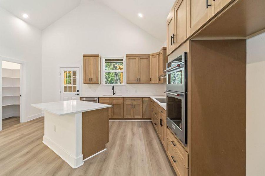 Kitchen featuring a center island, a high ceiling, decorative backsplash, and stainless steel appliances