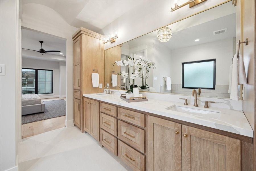 There are linen cabinets at both ends of the primary vanity cabinetry.