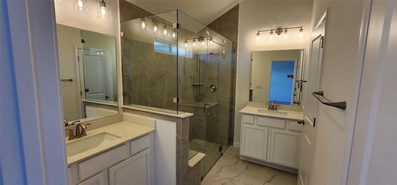 Bathroom featuring a stall shower, two vanities, and marble finish flooring Bathroom featuring a stall shower, two vanities, and marble finish flooring