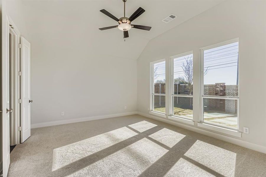 Unfurnished bedroom featuring light carpet, a ceiling fan, and vaulted ceiling