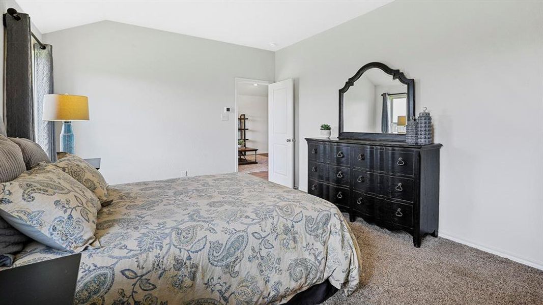 Vaulted ceiling bedroom with light gray walls, dark gray curtain panels, and neutral-toned carpeting