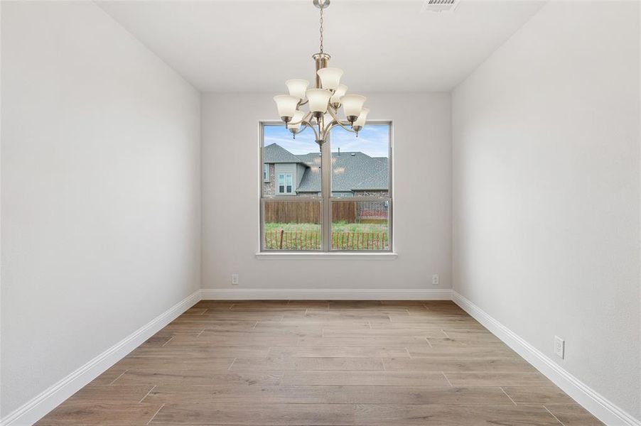 Unfurnished dining area with wood finish floors and a chandelier