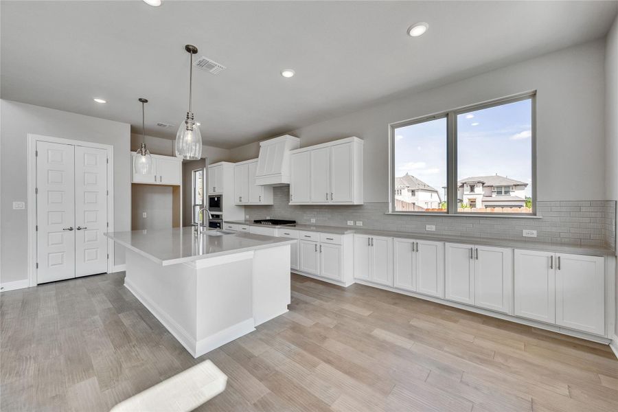 Kitchen with white cabinets, backsplash, a kitchen island with sink, decorative light fixtures, and recessed lighting Kitchen with white cabinets, backsplash, a kitchen island with sink, decorative light fixtures, and recessed lighting