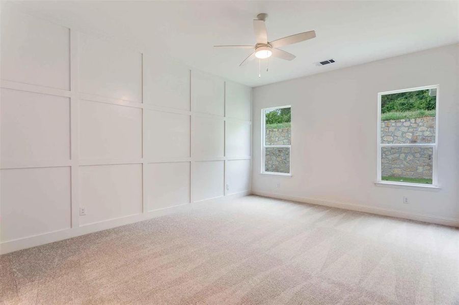 Spare room with light colored carpet, a decorative wall, and a ceiling fan
