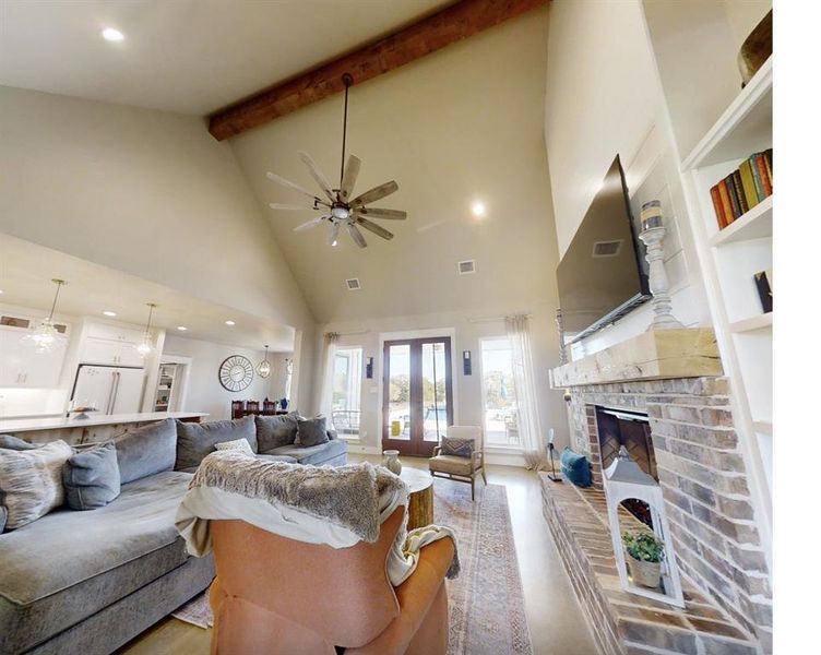 Living area with high vaulted ceiling, recessed lighting, ceiling fan, beamed ceiling, and a brick fireplace Living area with high vaulted ceiling, recessed lighting, ceiling fan, beamed ceiling, and a brick fireplace