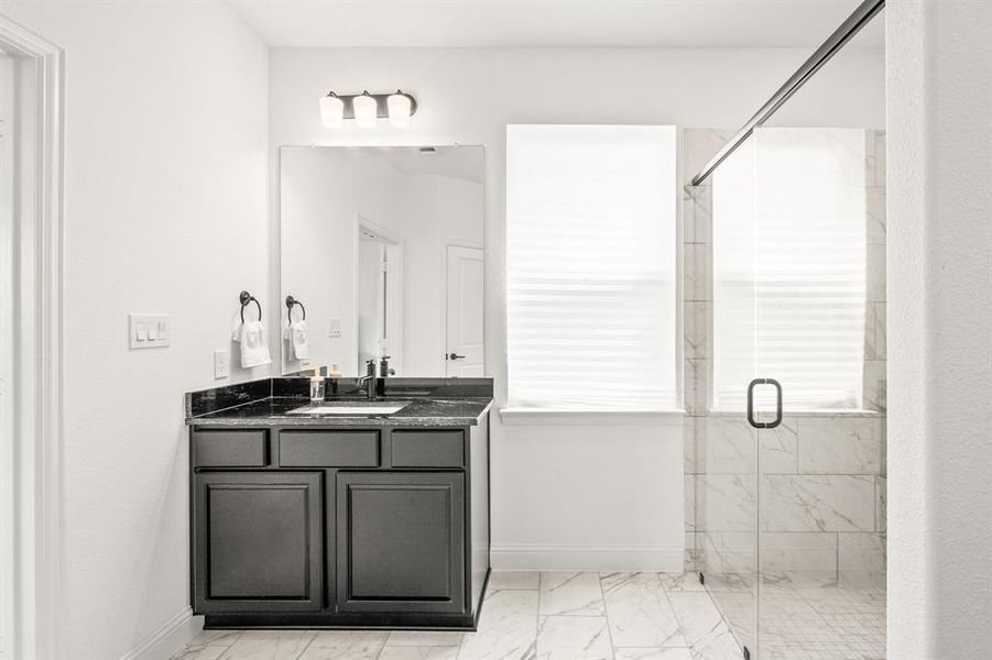 Bathroom with vanity, a marble finish shower, and light marble finish floors