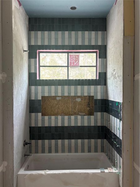 Bathroom featuring carefully selected tile in layered color and pattern.  Bathed in natural light, this space reflects a calm, elevated design.