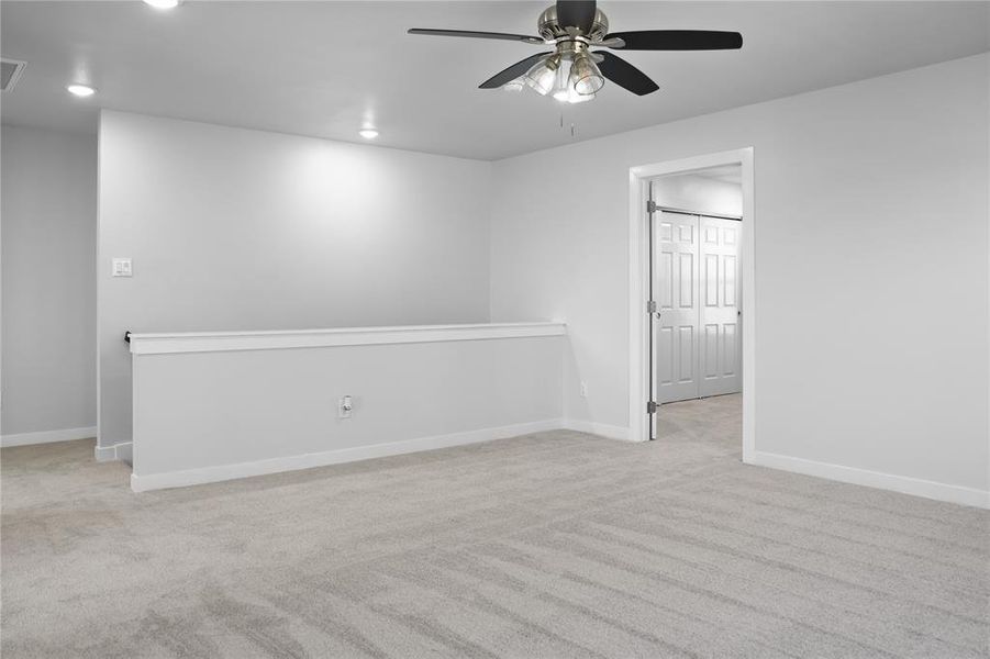 Empty room with ceiling fan and light carpet