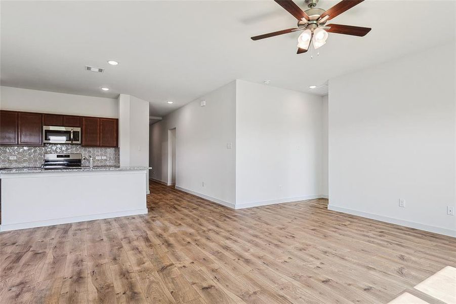 Kitchen with dark brown cabinetry, ceiling fan, decorative backsplash, light hardwood / wood-style floors, and appliances with stainless steel finishes