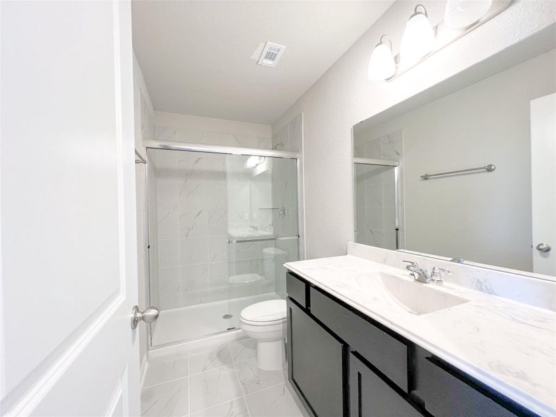 Bathroom featuring vanity, a shower stall, and light marble finish flooring