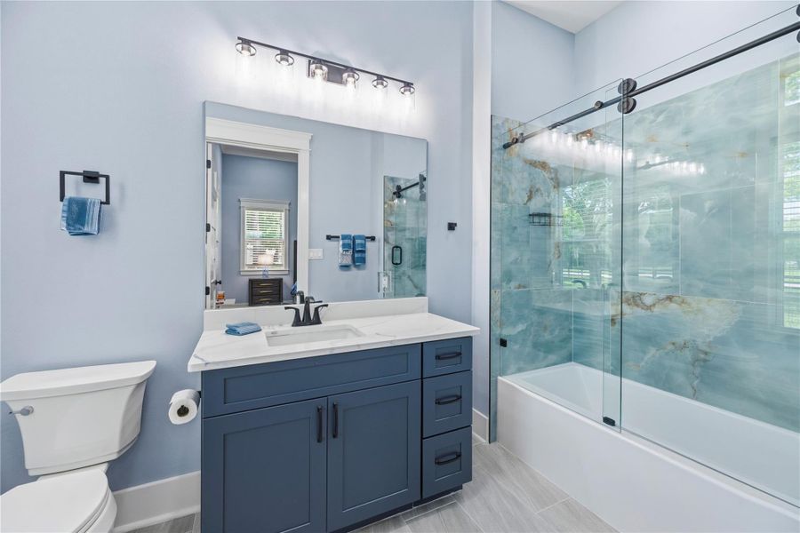 Refined full bath showcasing striking stone-inspired tile, custom glass enclosure, and elevated detailing.
