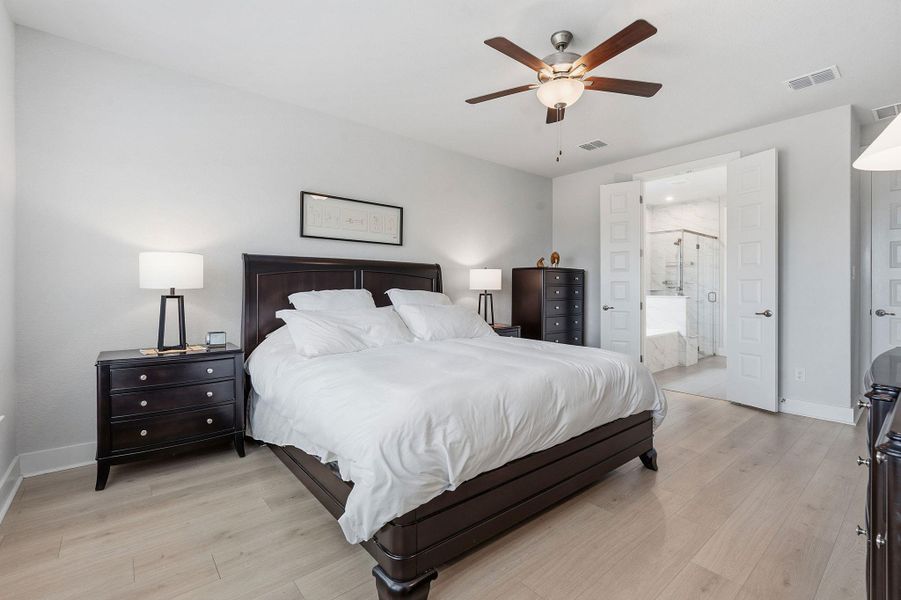 Bedroom with light wood-style floors, a ceiling fan, and ensuite bathroom