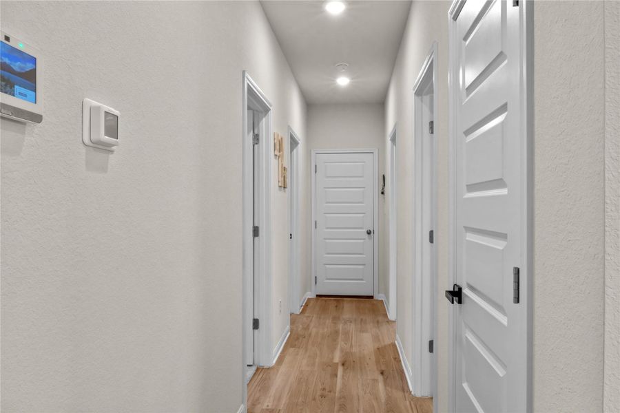 Hallway with a textured wall, light wood-style flooring, and recessed lighting